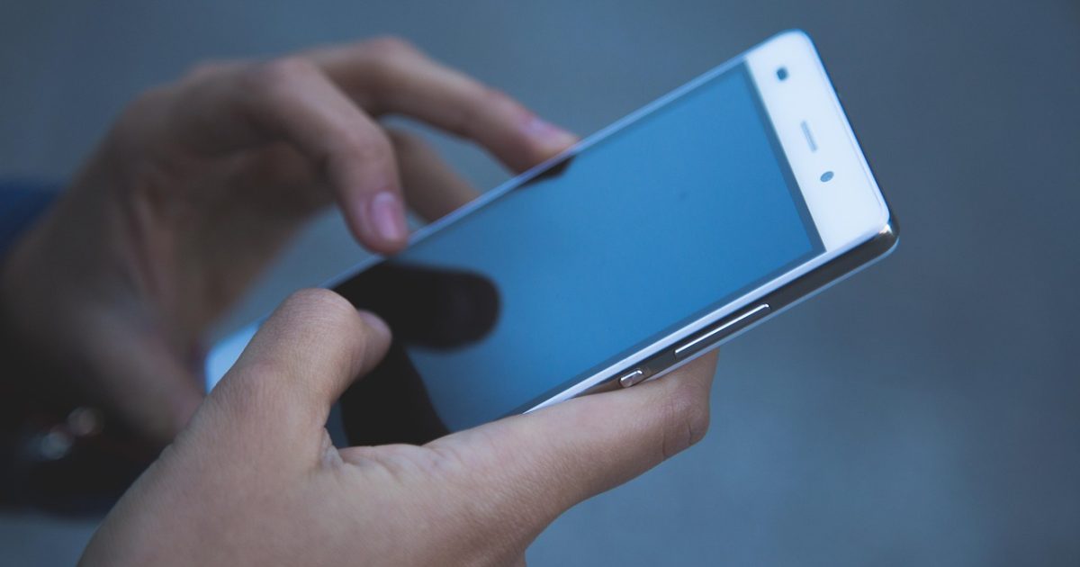 电话号码查询查询 手机屏幕上显示号码归属地查询结果页面，旁边放着记事本和铅笔，暖色台灯光下用户正在逐条核对陌生来电号码信息